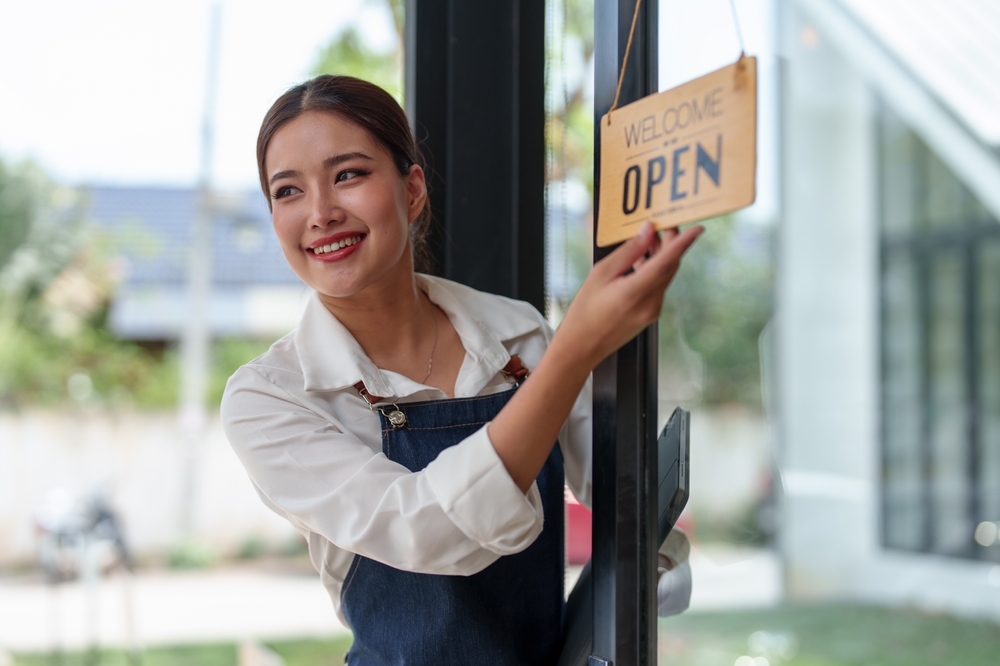 Starting a successful small business Small business owner SME Beauty Girl stands holding an open sign in front of a coffee shop. Coffee shop owner,
